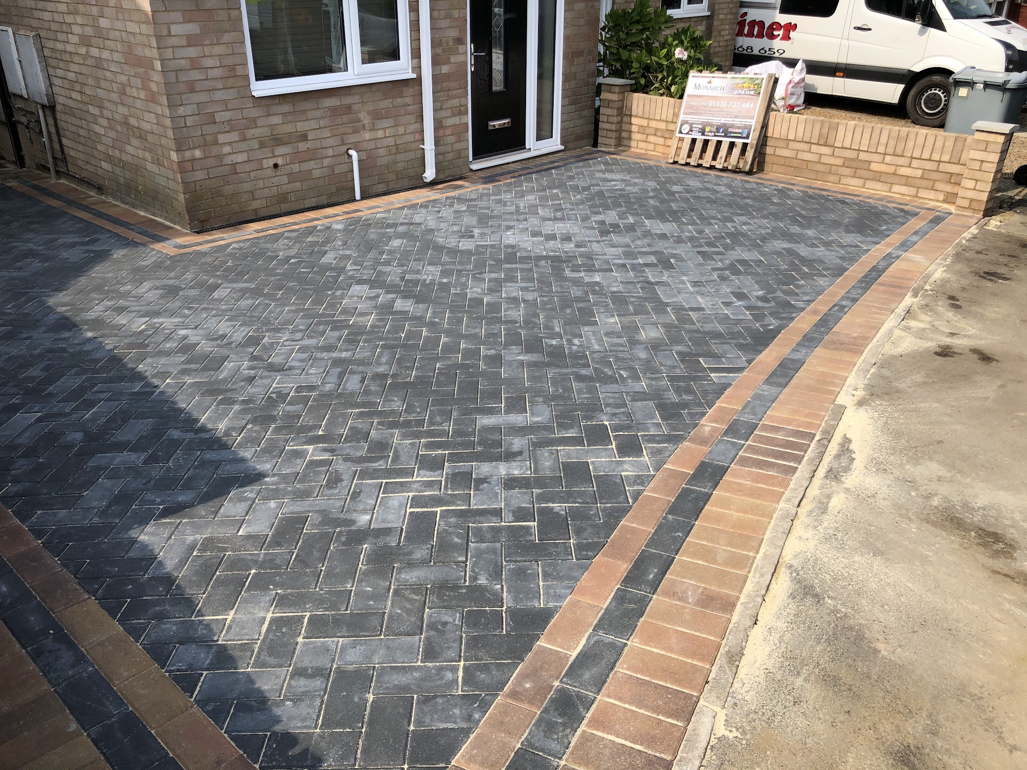 Finished charcoal block-paved driveway with a red brick border