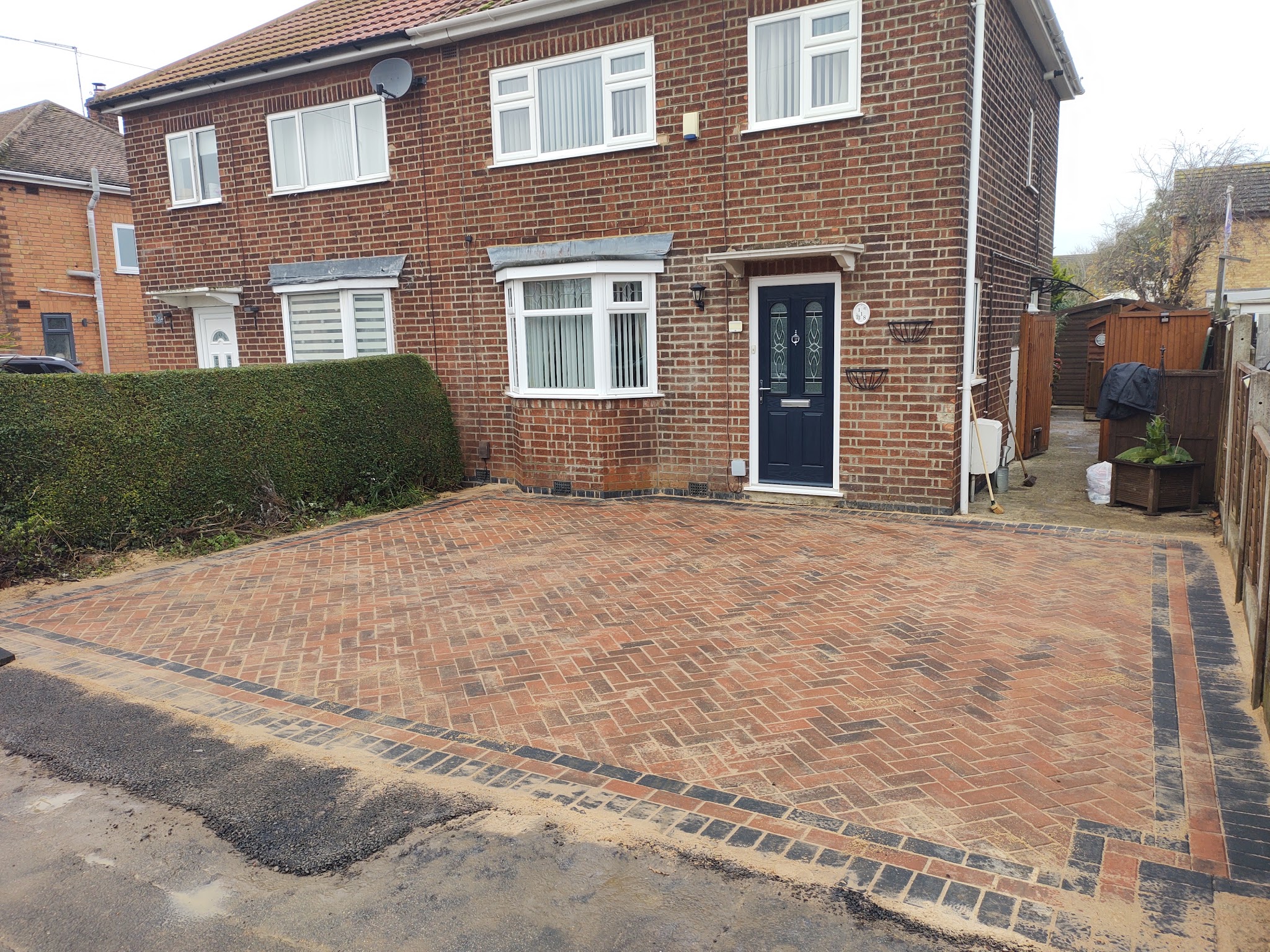 Finished red herringbone block-paved driveway with a charcoal border
