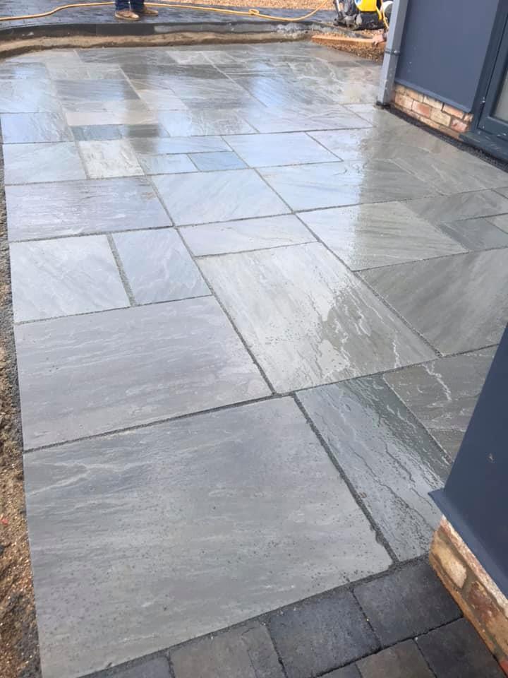 Grey natural stone patio slabs, freshly laid and wet from rain