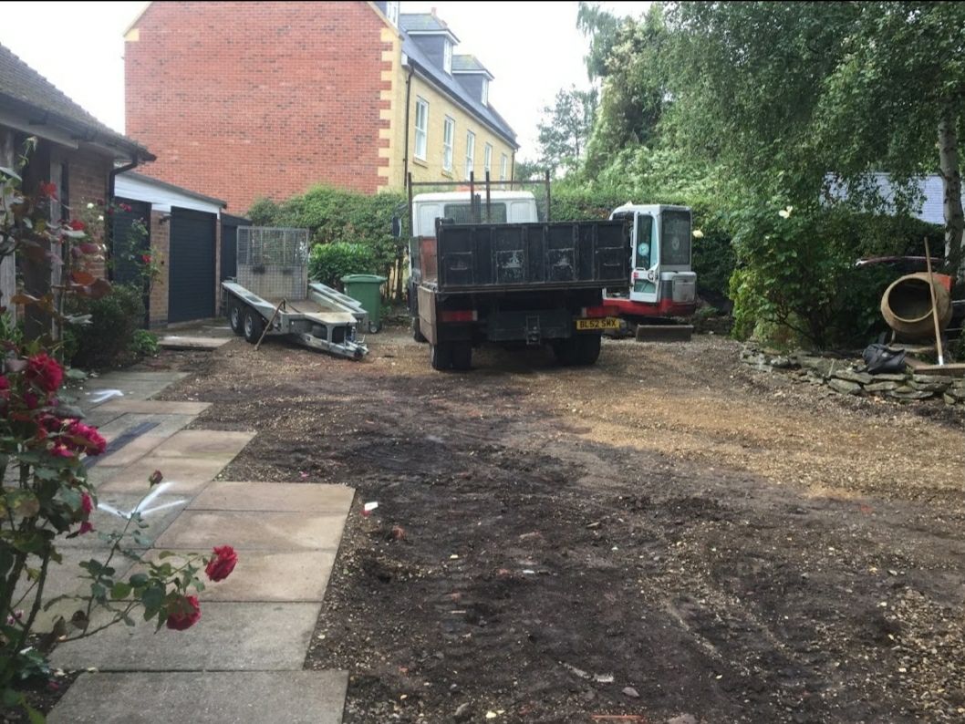 Old surface cleared from a front garden, with a tipper truck and digger on site