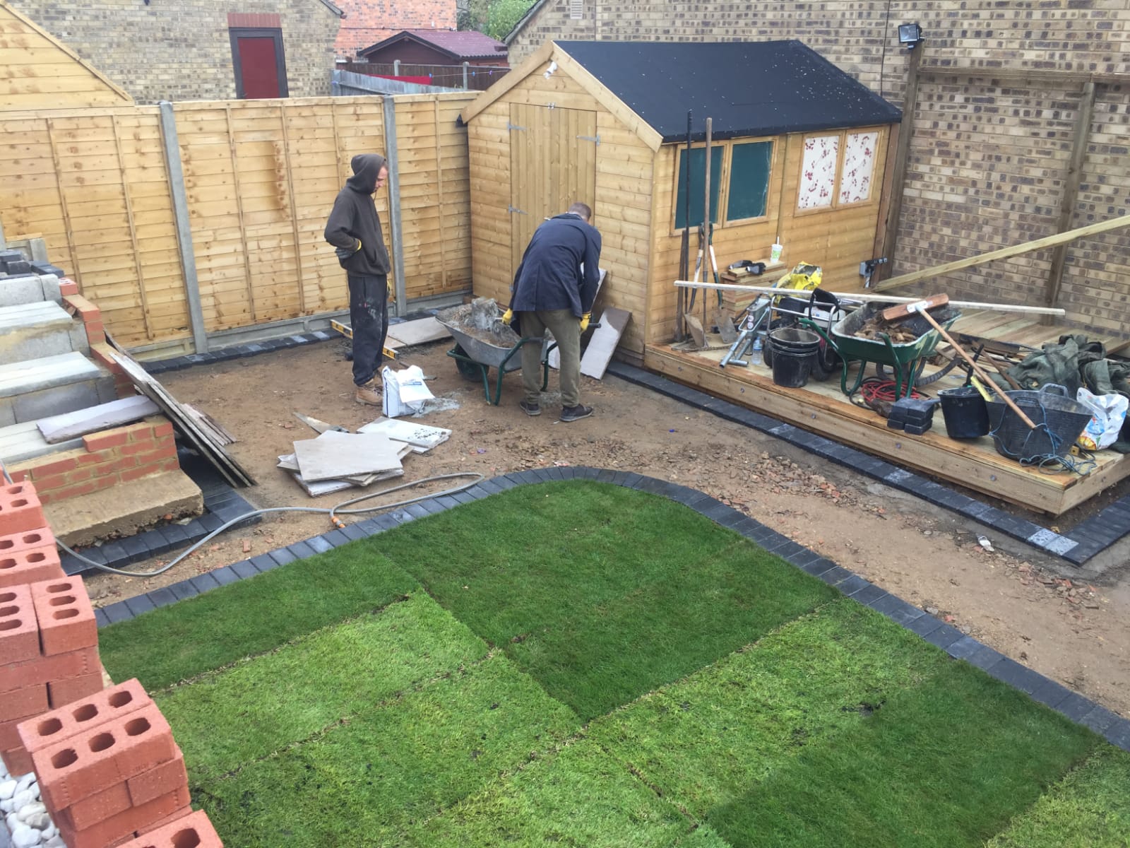 Garden makeover in progress with new turf, block edging, a shed and fence