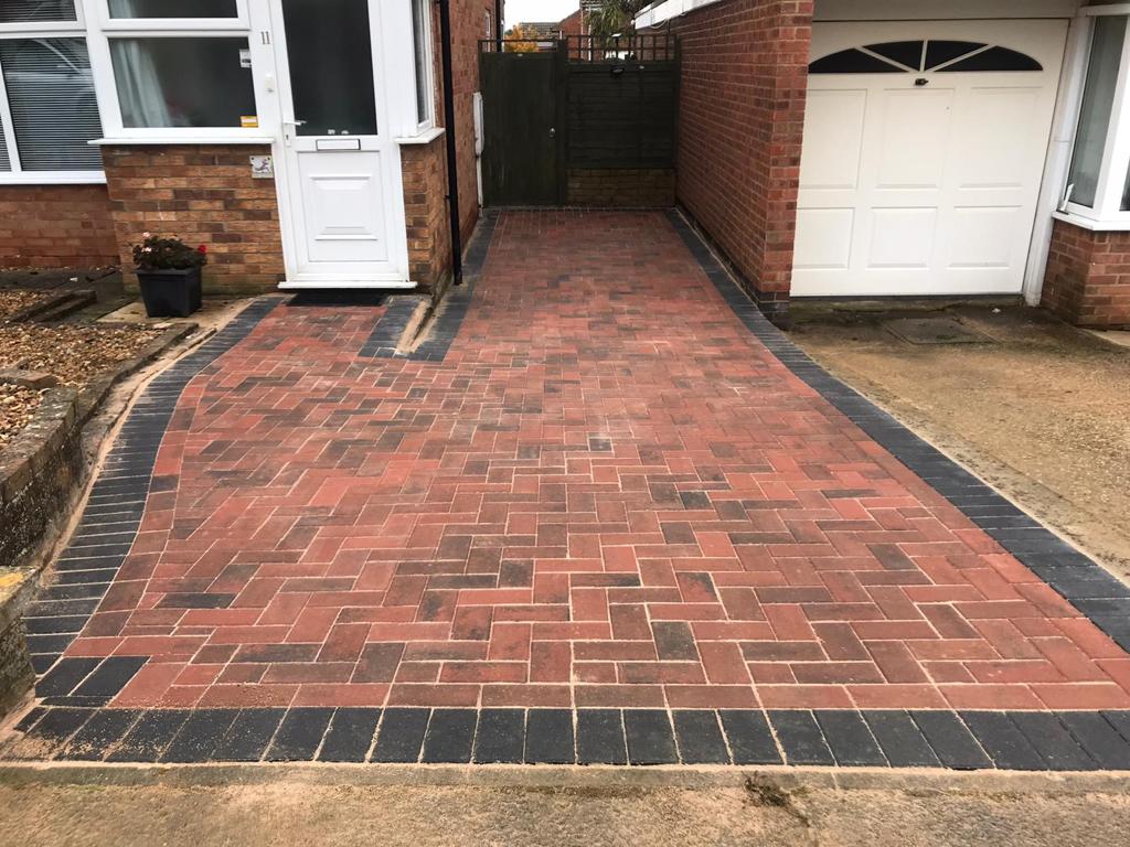 Finished red block-paved driveway with a charcoal border leading to a garage