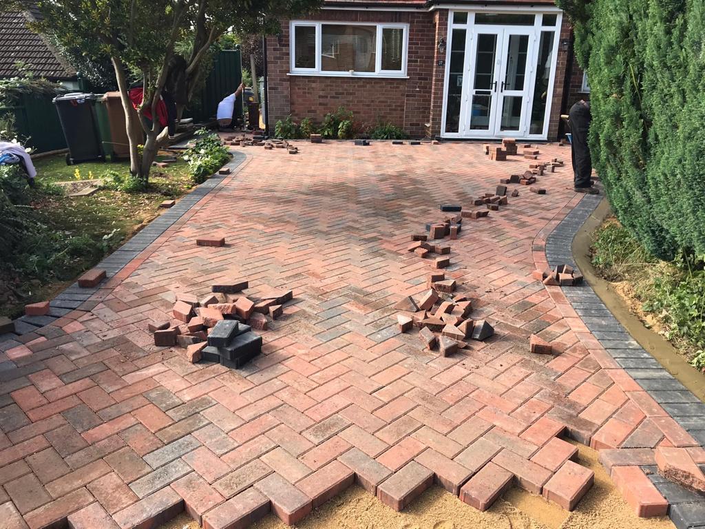 Red herringbone block paving being laid on a driveway
